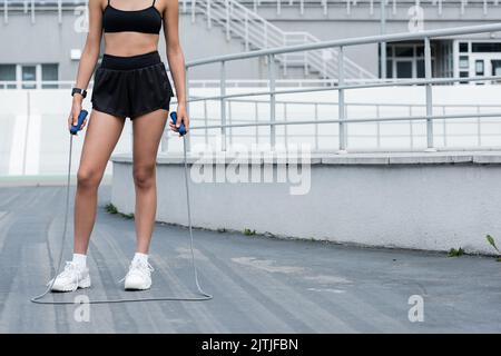 Partial view of african american sportswoman in shorts holding skipping rope on stadium Stock Photo