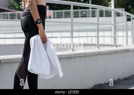 cropped view of african american woman in black leggings holding white terry towel Stock Photo