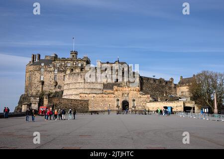 A group of tourists exploring the Edinburgh Castle under a clear sky Stock Photo