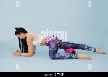 Myofascial relaxing massage Fitness, a fit girl doing fascia stretching in a studio on a blue background The concept of wellness, health, lifestyle, s Stock Photo