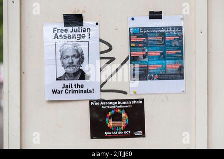Free Julian Assange posters on a hoarding in Whitehall, Westminster, London, UK. Advertising human chain protest around Parliament 8 October 2022 Stock Photo