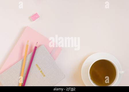 Notebooks, colored pencils, a cup of tea on a beige background with a copy space. Workplace of a student or student Stock Photo