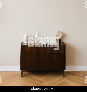 Classic wooden chest of drawers in a minimalist style with a decor of candles, vases in the living room Stock Photo
