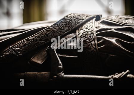 A closeup shot of Scottish designs on the belt and sword of an ancient effigy of the king Stock Photo