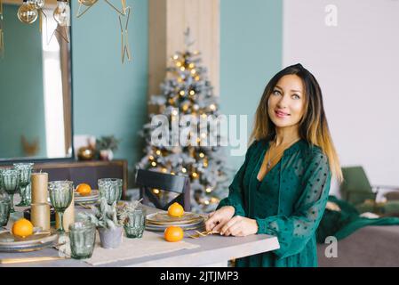 Pretty woman in a turquoise dress serves a festive table for the holiday Stock Photo