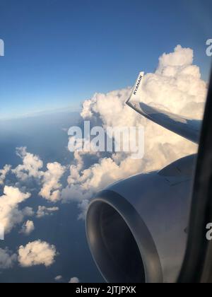 Trapani, Italy - 08.10.2022: Aerial airplane view on the clouds, engine and Ryanair logo on the airplane wing. View from inside the plane on white clouds Stock Photo