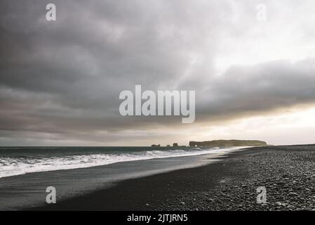 View of Cape Dyrholaey from the Reynisfjara beach with black volcanic sand, Iceland Stock Photo