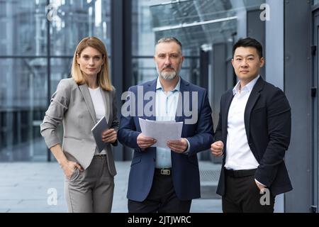 A team of experienced team leaders and specialists, a diverse group of business people, three people in business clothes are serious and focused in business clothes looking at the camera Stock Photo