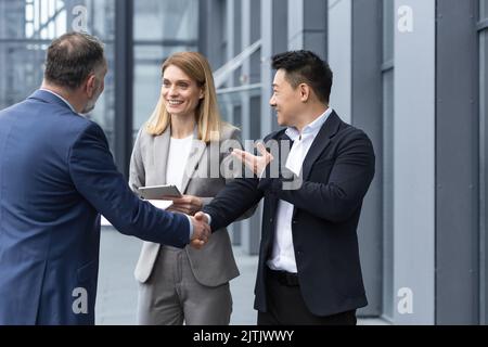 Three experienced managers team leaders, meet and get to know from outside the office team, diverse group of entrepreneurs shake hands men, introduce new colleague Stock Photo