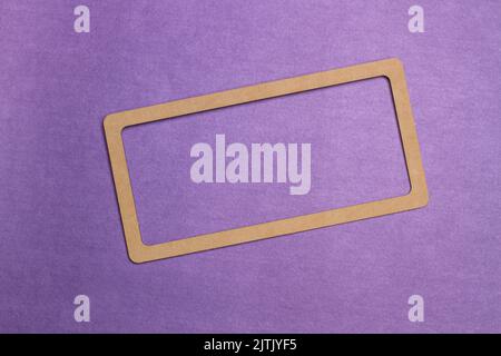 A brown cardboard frame on a purple background with copy space Stock Photo