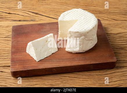 Frescal cheese, typical brazilian fresh white cheese with slice over wooden table. Stock Photo
