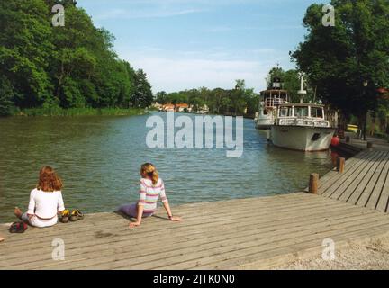 …STERG…TLAND Gšta Channel a canal dug by  soldiers from the Swedish regement through central Sweden.The work was led by Baltzar von Platen and the English engineer Thomas Telford.Two girls relax on the pier in Sšderkšping Stock Photo