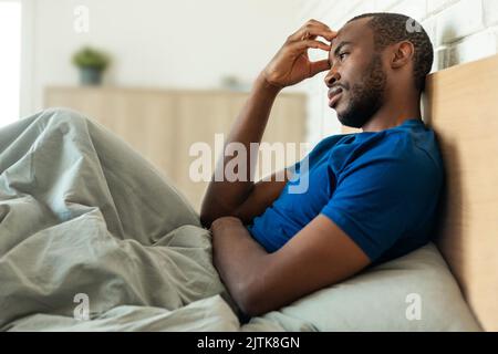 African American Man Thinking Touching Head Having Problems In Bedroom Stock Photo