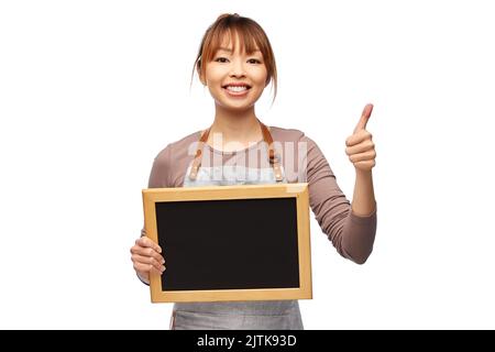 woman in apron with chalkboard showing thumbs up Stock Photo