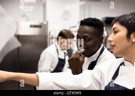 Smiling male and female colleagues having discussion in kitchen of restaurant Stock Photo