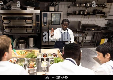 Chef explaining strategy to colleagues while holding digital tablet in kitchen of restaurant Stock Photo