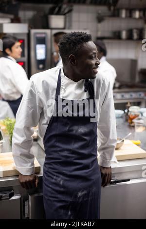 Happy man looking away while standing in commercial kitchen Stock Photo