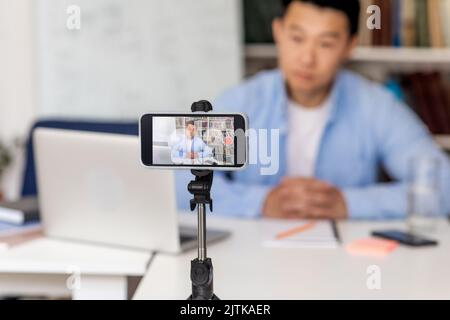 Chinese Male Teacher Making Video For Educational Blog At Workplace Stock Photo