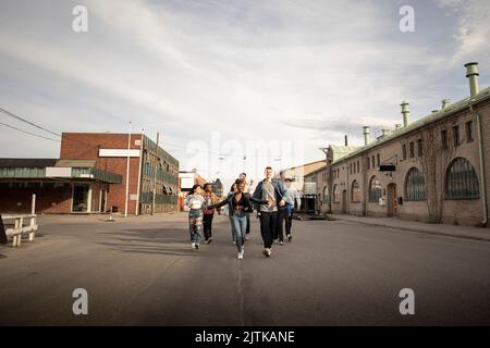 Carefree multiracial men and women running on street in city Stock Photo