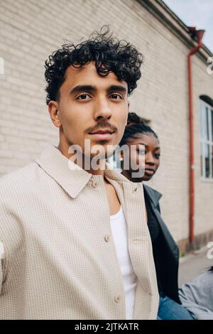Portrait of confident young man with friend outside building Stock Photo