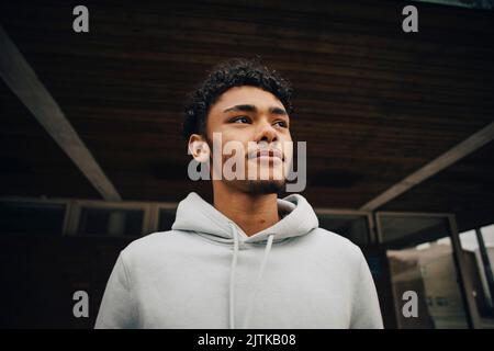 Young man looking away standing under bridge Stock Photo