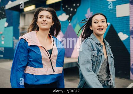 Smiling multiracial young women looking away while walking on street Stock Photo