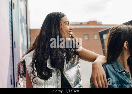 Happy young woman sitting by friend Stock Photo
