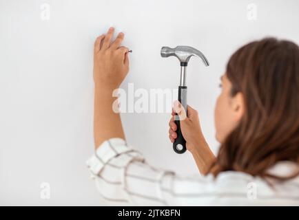 close up of woman hammering nail to wall at home Stock Photo