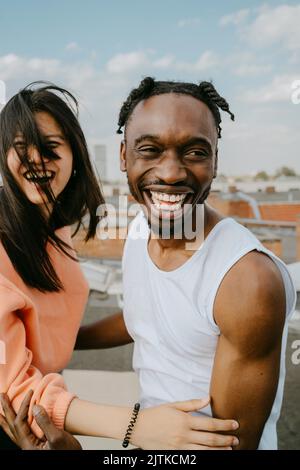 Multiracial cheerful male and female friends having fun on rooftop Stock Photo