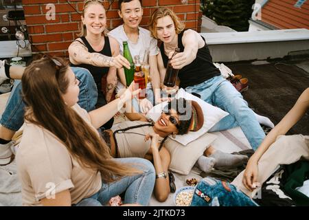 Happy male and female toasting beer bottles enjoying on rooftop Stock Photo