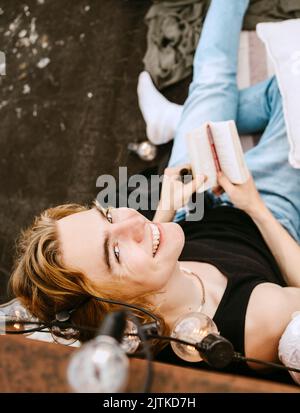 Portrait of smiling young man with book sitting on rooftop Stock Photo