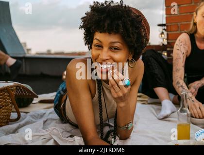 Portrait of smiling young woman lying on picnic blanket by female friend Stock Photo