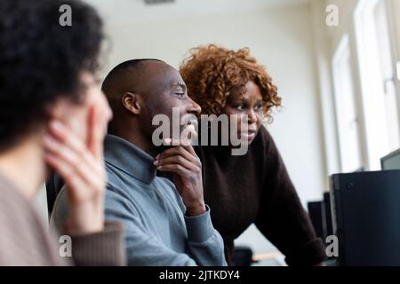 Businessman with hand on chin discussing with female colleagues in office Stock Photo