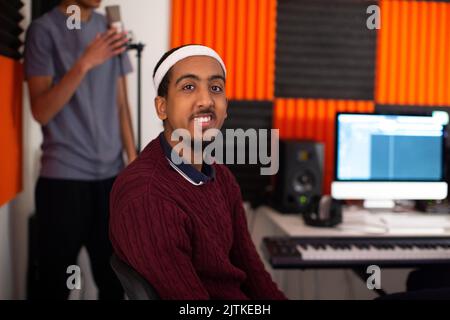 Portrait of smiling young man sitting in recording studio Stock Photo