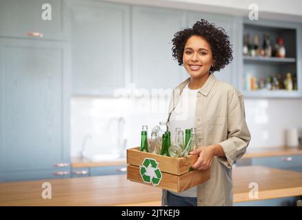 happy woman with bottles sorting glass waste Stock Photo
