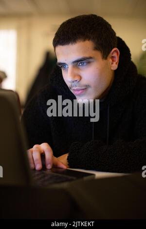 Teenage student using laptop in classroom Stock Photo