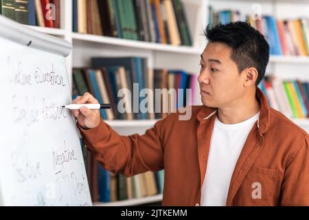 Chinese Male Tutor Writing On Whiteboard Having Class In Classroom Stock Photo
