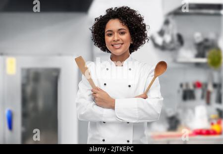 smiling female chef with wooden spoon and spatula Stock Photo