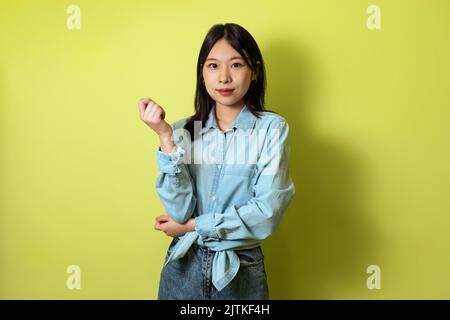 Japanese Millennial Lady Posing Looking At Camera Over Yellow Background Stock Photo