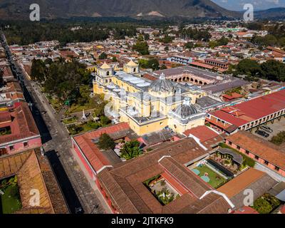 Beautiful aerial cinematic footage of the Antigua City in Guatemala, Its yellow church, the Santa Catalina Arch and the Acatenango Volcano Stock Photo