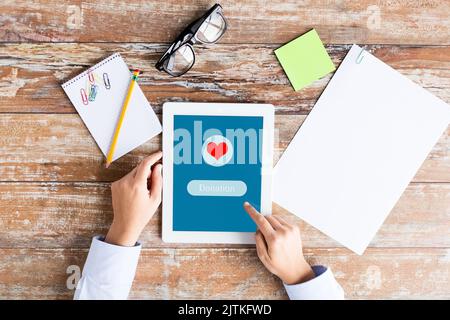 close up of hand with donate icon on tablet pc Stock Photo