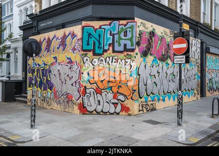 Boarded up shops covered in Graffiti, in preparation for the Notting Hill Carnival in West London, 2022. Stock Photo