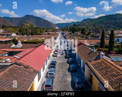 Beautiful aerial cinematic footage of the Antigua City in Guatemala, Its yellow church, the Santa Catalina Arch and the Acatenango Volcano Stock Photo