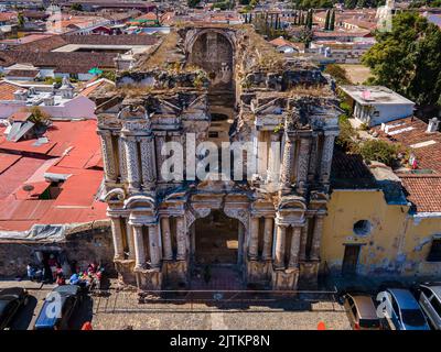 Beautiful aerial cinematic footage of the Antigua City in Guatemala, Its yellow church, the Santa Catalina Arch and the Acatenango Volcano Stock Photo