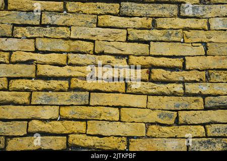 Background of weathered old yellow brick wall. Stock Photo