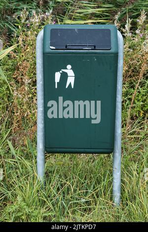 Green garbage bin with a stylized image of a person throwing garbage into a trash can. Stock Photo