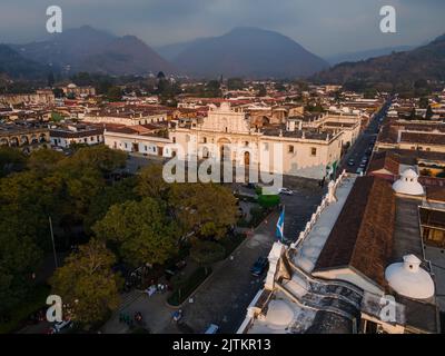 Beautiful aerial cinematic footage of the Antigua City in Guatemala, Its yellow church, the Santa Catalina Arch and the Acatenango Volcano Stock Photo