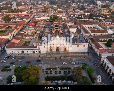 Beautiful aerial cinematic footage of the Antigua City in Guatemala, Its yellow church, the Santa Catalina Arch and the Acatenango Volcano Stock Photo