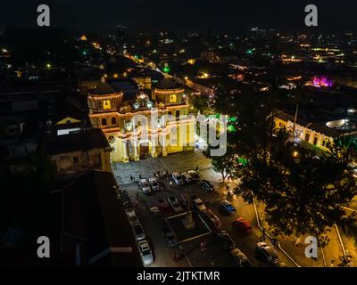 Beautiful aerial cinematic footage of the Antigua City in Guatemala, Its yellow church, the Santa Catalina Arch and the Acatenango Volcano Stock Photo