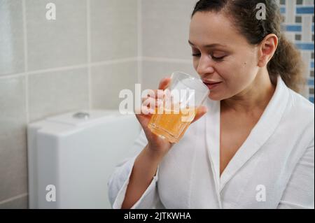 Charming woman drinks water with effervescent painkiller pills. Suffering from headache. Migraine fever. Pain relievers Stock Photo